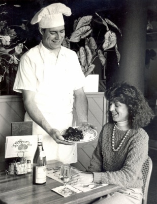 TIMES-SHAMROCK ARCHIVES Mark Cooper serves a blackened red fish to his brother, Jack Cooper’s, wife, Angela Menichillo Cooper, on March 8, 1986.